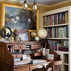 an old desk with books and globes on it in front of a bookcase