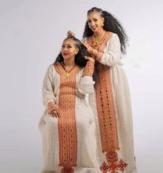 two women dressed in ethnic clothing posing for the camera with their arms around each other