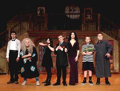 a group of people standing on top of a wooden floor in front of a stage