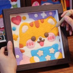 a person is painting an animal with felt in a wooden frame on top of a table