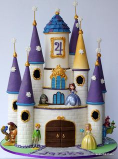 a cake that is shaped like a castle with princess figures on the front and sides