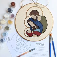 the embroidery pattern is being worked on with paint and crayon pencils next to it