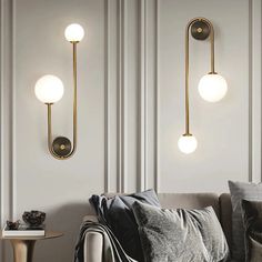 three lights are hanging on the wall above a couch in a room with white walls