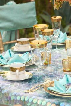 the table is set with blue and gold plates, silverware, and napkins