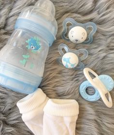 a baby's bottle, pacifier and bib lay on a fur surface