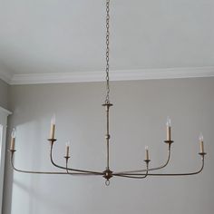 a chandelier hanging from the ceiling in a room with white walls and windows