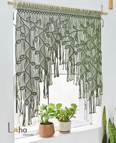 a green curtain hanging over a window next to two potted plants on a windowsill