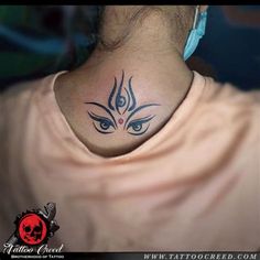 a person with a tattoo on their neck and behind the neck is an evil eye