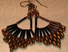 a pair of black and gold earrings hanging from a hook on a white tablecloth