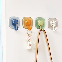 the key holder is hanging on the wall with three hooks and a leather bag strap