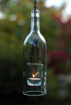 a candle in a glass bottle hanging from a chain