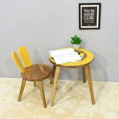 two wooden chairs sitting next to each other in front of a table with a book on it