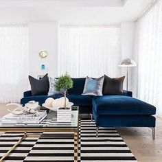 a living room with a blue couch and black and white rugs on the floor