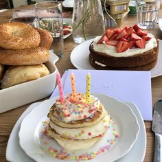 a table topped with cakes covered in frosting and strawberries next to buns