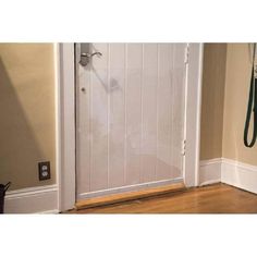 a white door with a green hose hanging from it's side and a brown wall in the background