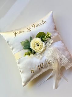 a wedding ring pillow with a white rose on it