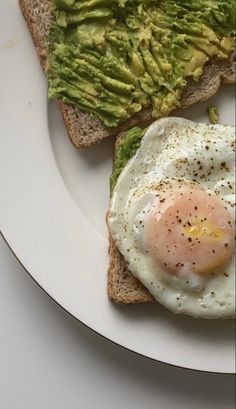 an egg and toast with avocado on it are sitting on a white plate