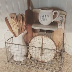 kitchen utensils and wooden spoons sit in a wire basket on the counter