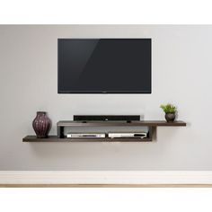 a flat screen tv mounted to the side of a wall with two vases next to it