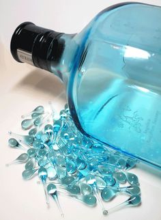 a bottle filled with blue glass beads on top of a white table next to other items