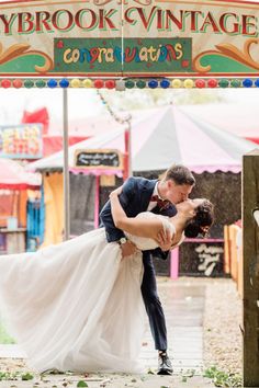 a bride and groom kissing in front of a carnival sign