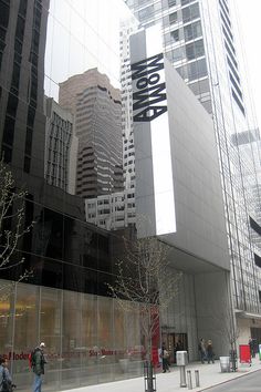 people are walking on the sidewalk in front of some tall buildings with glass walls and windows