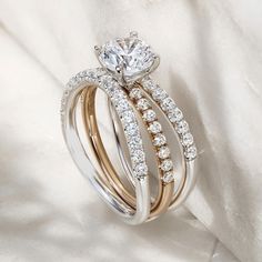 two wedding rings with diamonds on them sitting on a white satin surface in front of the camera