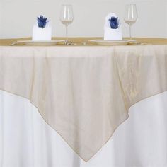 two wine glasses sitting on top of a table next to white napkins and blue flowers