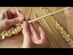 two hands are holding chopsticks over some gold origami pieces on a table