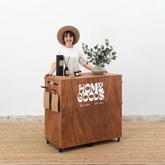 a woman in a hat standing behind a wooden box with some plants on top of it