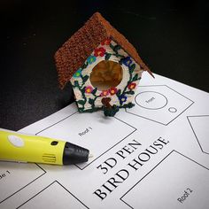 a birdhouse is sitting on top of a paper with a marker next to it