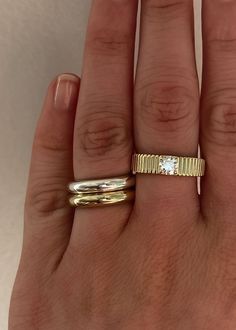 a woman's hand with two gold rings on it and one white diamond in the middle