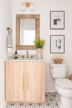 a white toilet sitting next to a bathroom sink under a mirror and a wooden cabinet