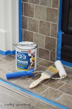 a paint can and brush sitting on the floor next to a fireplace with blue trim