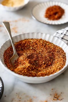 a white bowl filled with spices on top of a table next to two bowls of seasoning