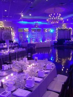 the tables are set up for a formal function with purple lighting and white linens