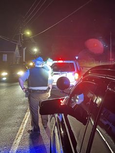 two police officers standing next to cars at night