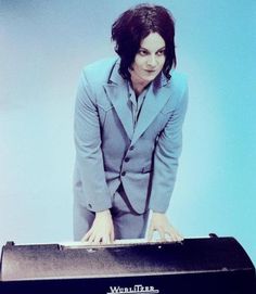 a man in a suit is playing an electronic keyboard and posing for the camera with his hands on top of it