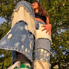 a woman standing on top of a pair of jeans with her feet in the air