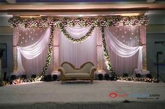 a couch sitting in front of a stage decorated with flowers