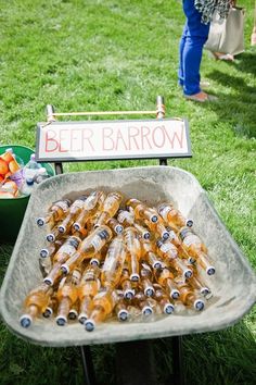 there is a tray full of beer bottles on the grass with people in the background