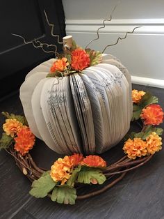 a white pumpkin decorated with orange and yellow flowers sitting on top of a wooden floor