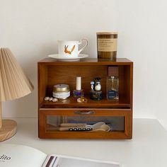 an open book on a table next to a wooden shelf with various items in it