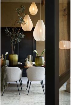 the dining room table is surrounded by hanging lights and vases with plants in them