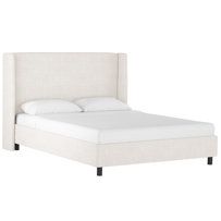 the bed is made up with white linens and black wood legs on each side