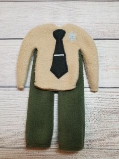 a stuffed animal with a tie on it's shirt and pants, sitting on a wooden floor