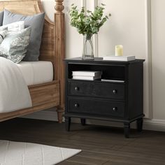 a bedroom with a bed, night stand and flowers on the nightstand next to it