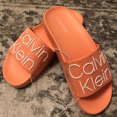 I Have Womens Sizes 6 And 7. These Are Calvin Klein Style Axel Logo Slides. Perfect For The Pool Or Around The House. Comfortable, Durable, And Stylish Slides To Go About Your Day In. The Color Is A Nice Salmon, These Are Unisex Calvin Klein Sandals For Spring Vacation, Trendy Calvin Klein Open Toe Sandals, Trendy Calvin Klein Sandals For Spring, Calvin Klein Casual Sandals For Vacation, Casual Calvin Klein Sandals For Vacation, Calvin Klein Open Toe Sandals With Cushioned Footbed, Calvin Klein Casual Sandals With Cushioned Footbed, Casual Calvin Klein Sandals With Cushioned Footbed, Calvin Klein Synthetic Slip-on Sandals