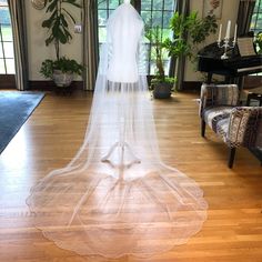 a bridal gown on display in a large room with wooden floors and plants behind it