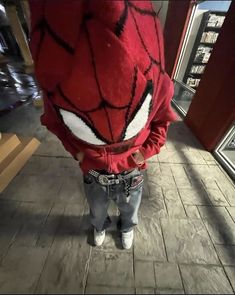 a person wearing a spider man costume standing in front of a store window with his hands on his hips